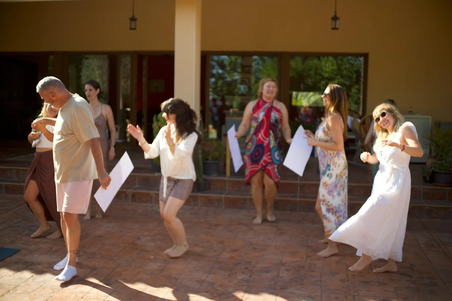 A mixed group dancing together in a sunlit outdoor courtyard