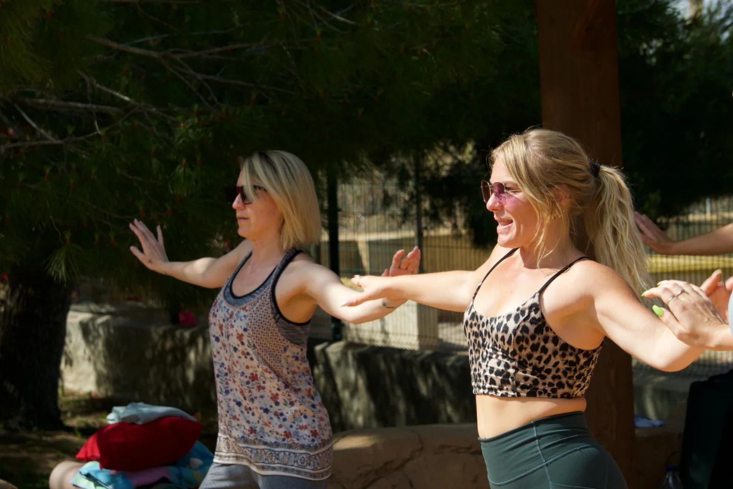 Two women extending their arms during an outdoor movement session